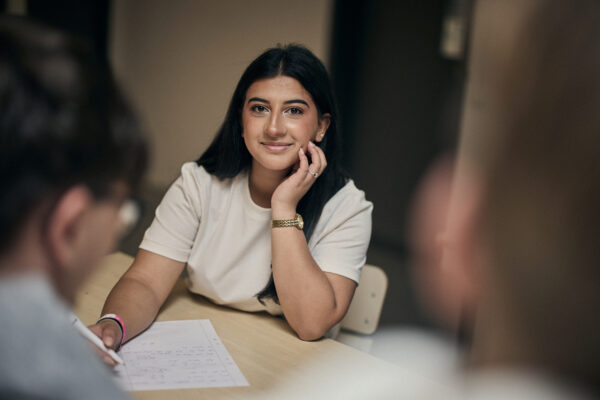Elev sitter vid ett bord och antecknar under lektion på Varbergs Enskilda Gymnasieskola.