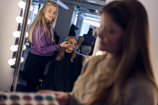 Stylistprogrammet på Varbergs Enskilda där elev sminkar modell vid sminkspegel i skolans kreativa studio.