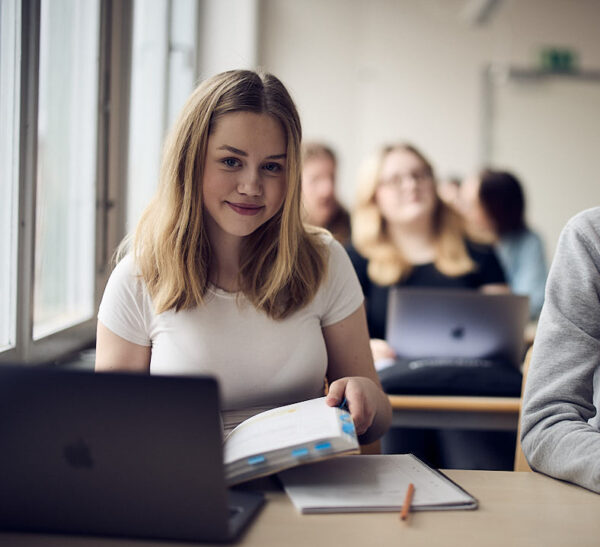 Elev tittar upp från boken under lektion på Varbergs Enskilda Gymnasieskola. Studiematerial och laptop är i fokus.