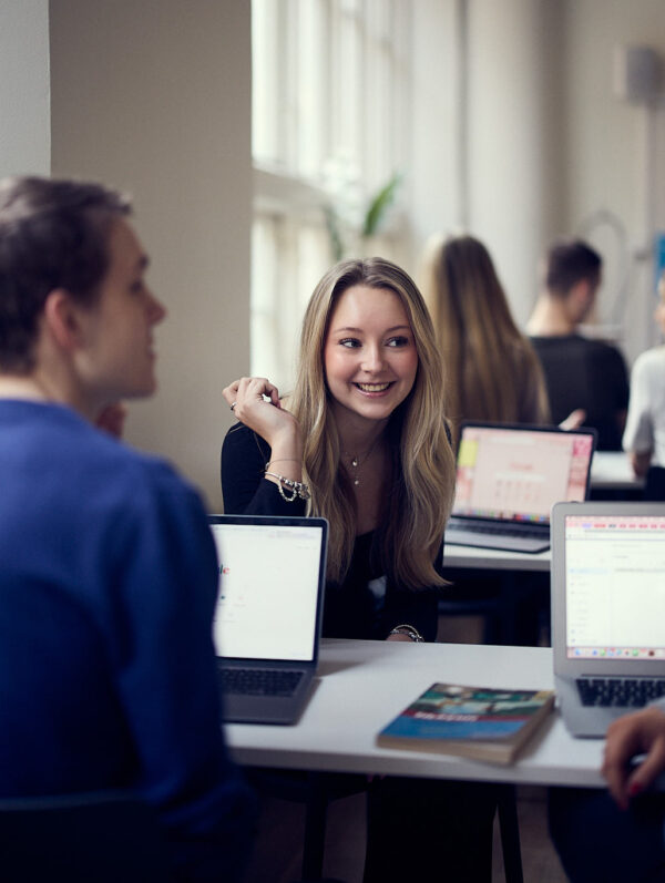 Elever samarbetar i grupp vid laptops under en lektion.