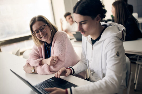 Elev visar sitt arbete på laptop för lärare under gymnasieundervisning på Varbergs Enskilda Gymnasieskola.