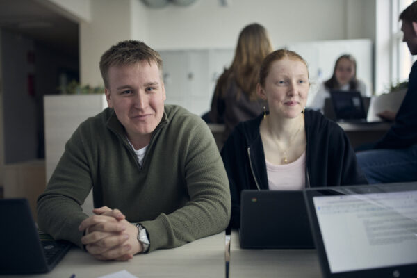 Två elever samarbetar med datorer under en lektion.